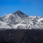 Stunning view of Mount Everest surrounded by snowy peaks under a clear blue sky.